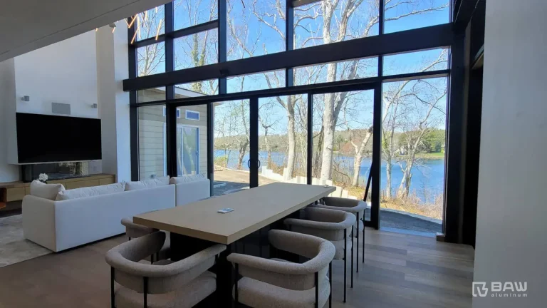 Large living and dining room with a wall of windows overlooking a lake